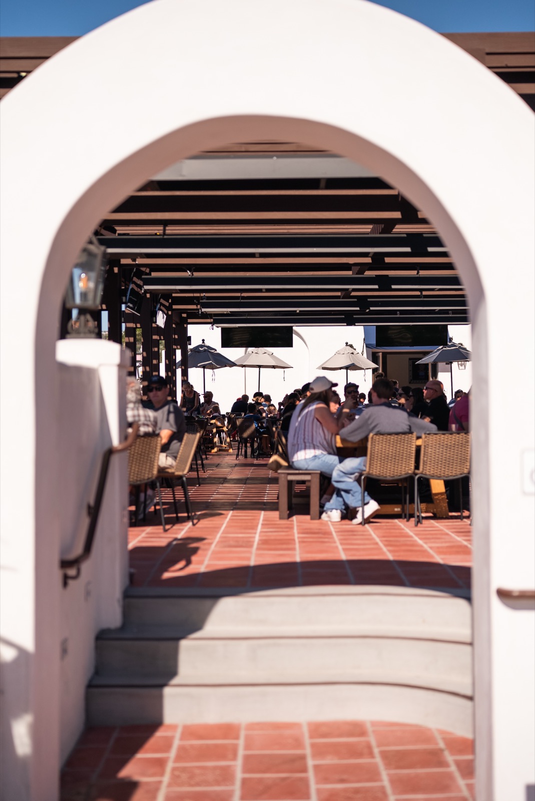 Guests dining on Miramar Food Hall's sunlit patio, framed by the building's signature arch